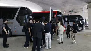 Koreańscy migranci wsiadający na lotnisku do autobusów