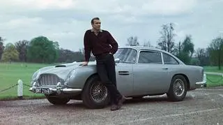Sean Connery jako James Bond i jego Aston Martin DB5. Kadr z filmu "Goldfinger" z 1964 roku