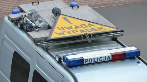 policyjny radiowóz, na dachu znak ostrzegawczy z napisem 'uwaga wypadek'