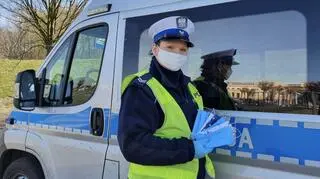 Policjantka rozdaje maseczki na służbie
