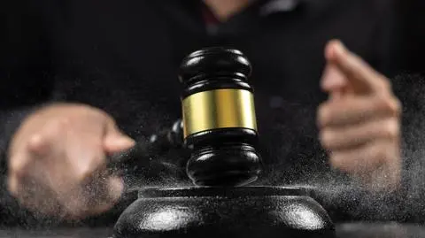 shutterstock_2542900411 Aukcjoner, sprzedawca z młotem na aukcji publicznej, szlifierz z młotem aukcyjnym do zamknięcia licytacji. Uderza młotkiem w zakurzony stół, kurz leci we wszystkich kierunkach