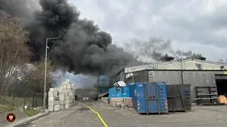 Wysoki słup dymu, ogień wewnątrz hali