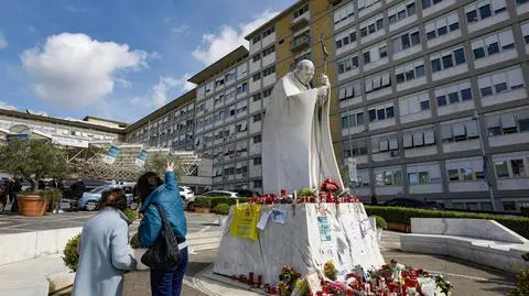 Ludzie modlą się przed pomnikiem Jana Pawła II przy wejściu do szpitala Gemelli, gdzie leczony jest papież Franciszek w Rzymie we Włoszech