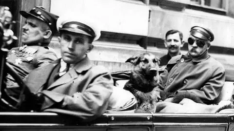 Na tylnym siedzeniu samochodu siedzą: Józef Piłsudski (po lewej stronie, w goglach), mjr Konrad Zembrzuski (z prawej) i pies "Pies". Samochód prowadzi szofer Zygmunt Malinowski, obok niego siedzi wachmistrz Walenty Wójcik.1929-07-11
