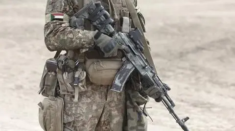 Żołnierz z karabinem maszynowym i flagą Sudanu na mundurze wojskowym