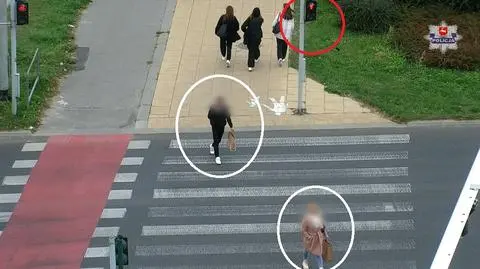 Pali się czerwone. Piesi przechodzą. Jeden z nich korzysta z telefonu 