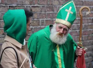 Dzień św. Patryka. Turysta rozmawia z mężczyzną przebranym za św. Patryka w Temple Bar w Dublinie