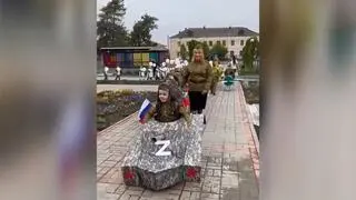 Dzieci przebrane za rosyjskich żołnierzy i w kartonowych czołgach z replikami karabinów z literami Z