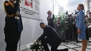 Prezydent RP Karol Nawrocki i pierwsza dama Marta Nawrocka składają kwiaty przed tablicą upamiętniającą posłów i senatorów - ofiary katastrofy pod Smoleńskiem
