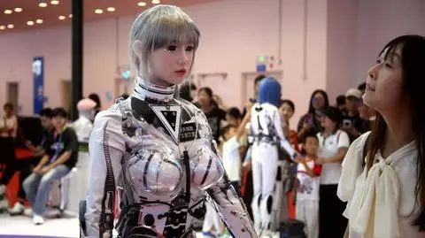 Uczestnik Światowej Konferencji Robotycznej 2025 w Pekinie ogląda humanoidalnego robota bionicznego, Chiny, 12 sierpnia 2025 r.