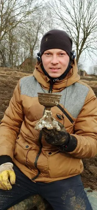 Prezes "Grossusa" Grzegorz Dańczuk pokazuje, wykonaną z przerobionego kielicha, lampę naftową