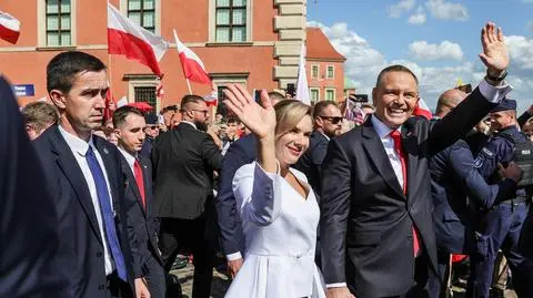 Prezydent Karol Nawrocki wraz z małżonką pozdrawiają tłum zgromadzony przez Zamkiem Królewskim w Warszawie