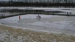 Zabawa dzieci i dorosłych na zamarzniętym zbiorniku wodnym