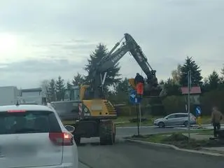 Stał na łyżce od koparki i montował znak