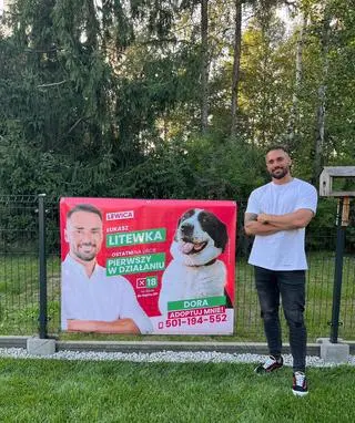 Łukasz Litewka przy swoim bannerze z psami do adopcji