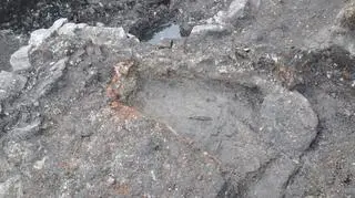Zniszczony fragment podłogi z płytek ceglanych w „kapliczce” przy źródle