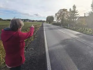 Pani Lidia, mieszkanka Pławinka, pokazuje nam, w którym miejscu znajduje się przystanek autobusowy oraz jak niebezpieczny jest to odcinek drogi