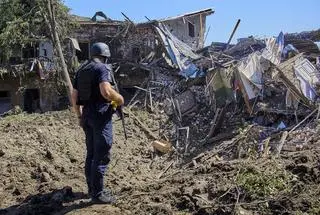 Policjant sprawdza obszar z gruzami budynku zniszczonego po ostrzale w Charkowie w Ukrainie (09.07.2022)