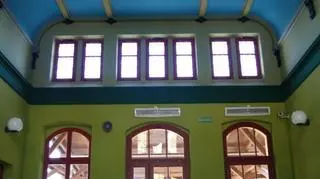 W holu stoją odrestaurowane drewniane ławki