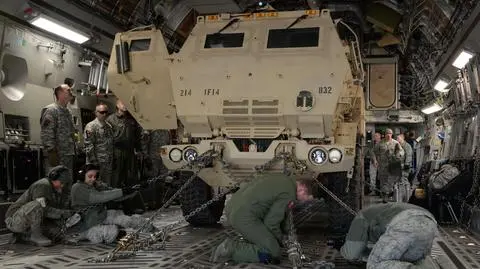 Żołnierze mocują wyrzutnię pocisków HIMARS w ładowni ciężkiego samolotu transportowego C-17A