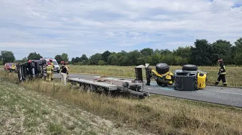 Samochód na boku, z przyczepy spadła koparka