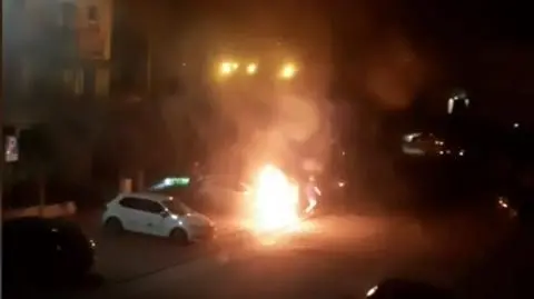 Na parkingu spłonął samochód, dwa inne zostały uszkodzone. Jedna osoba ranna