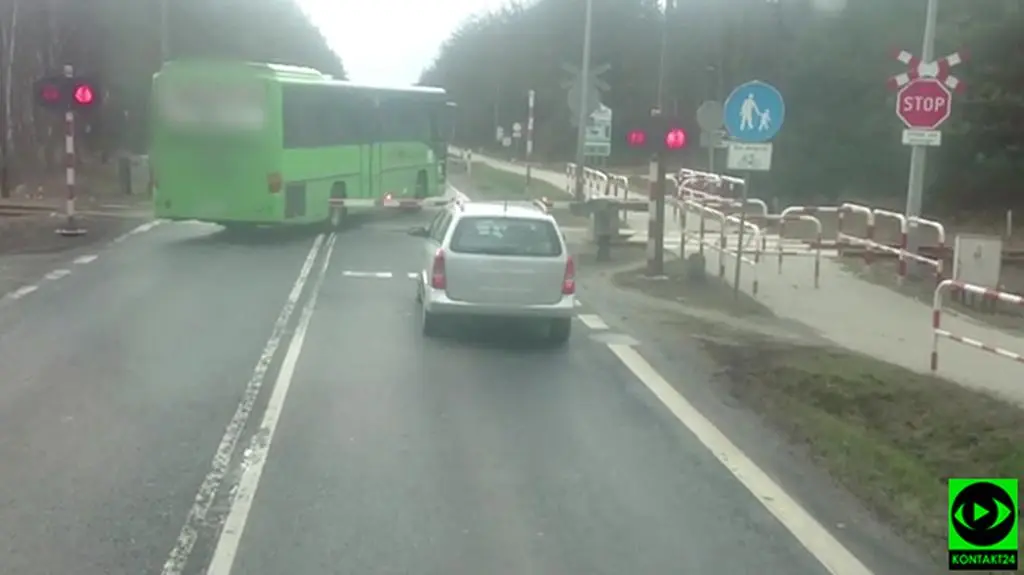 Kierowcy stoją autokar jedzie. Przez zamknięty przejazd chwilę przed szynobusem
