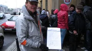 Kolejkowy porządkowy prezentuje listę... kolejkowiczów. Wrocław, poniedziałkowy poranek przed siedzibą NBP.