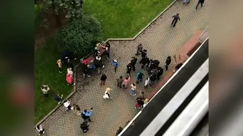 Grupa mężczyzn z pałkami zbliża się do kawiarni 