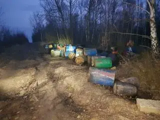 Beczki wyrzucone przy leśnej drodze