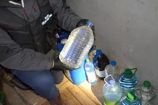 Obok linii produkcyjnej stały baniaki z alkoholem