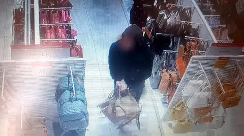 Mężczyzna wynosi damskie torebki