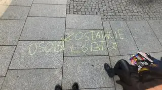 "Leave LGBTQ+ people alone" written with yellow chalk on the pavement