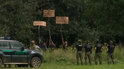 Migranci na granicy komunikują się za pomocą kartonów z napisami. Piszą, że są chorzy