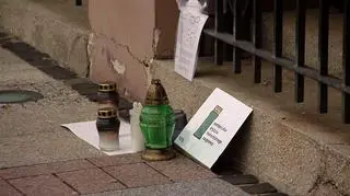 Przy wstawie stoją znicze