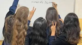 Uczennice piszące na tablicy "Women, life, freedom", jedno z głównych haseł protestów kobiet w Iranie