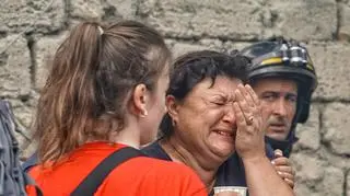 Odessa. Zniszczenia po rosyjskim ataku rakietowym. Funckcjonariusze służb ratowniczych obok bliskich mężczyzny, który zginął w wyniku rosyjskiego ataku