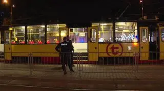 Tramwaj, a w nim pasażerka czeka na służby pod okiem policji