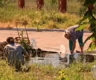 Cywile, którzy nabierają wodę do butelek wprost z kałuży na ulicy w Mariupolu