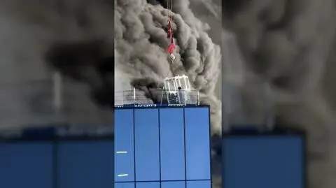 Mężczyzna uwięziony na dachu płonącego budynku, dramatyczna interwencja operatora dźwigu. Nagranie