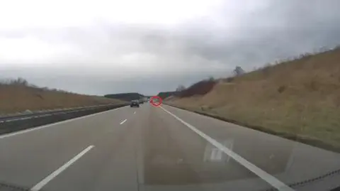 Kierowca BMW wyprzedza ciężarówkę pasem awaryjnym na autostradzie