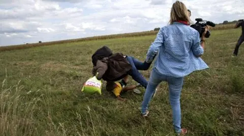 Imigranci uciekają przed policją. Operatorka kamery kopie i podstawia im nogę