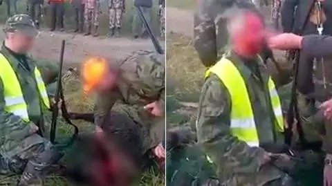 Myśliwy klęczy, a jego koledzy się śmieją i malują mu twarz krwią zastrzelonego dzika