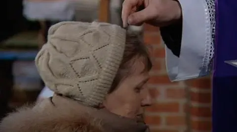 Podczas mszy duchowny posypuje głowy popiołem