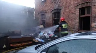 Strażacy gaszą śmieci ze spalonego mieszkania