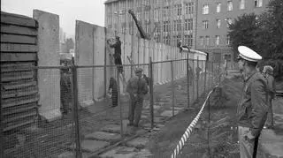 Ekipa budowlana wypełnia betonowe segmenty ściany granicznej     