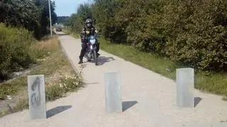 Przed chodnikiem stoją betonowe słupy