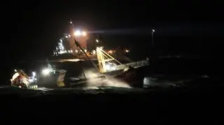Zdjęcie zrobione ze statku straży przybrzeżnej przedstawiające nocną akcję ratunkową