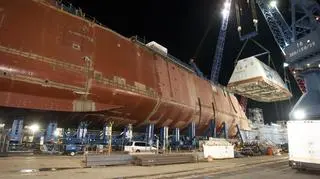 Zumwalt podczas budowy. Dźwigi przenoszą na miejsce nadbudówkę, która została przywieziona do stoczni już w całości