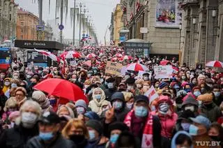 Kolumna protestujących maszeruje chodnikiem wzdłuż alei Niepodległości 